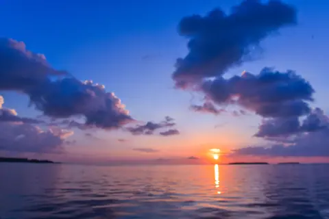 A breathtaking view of a tropical sunset with vibrant colors reflecting on the calm sea.