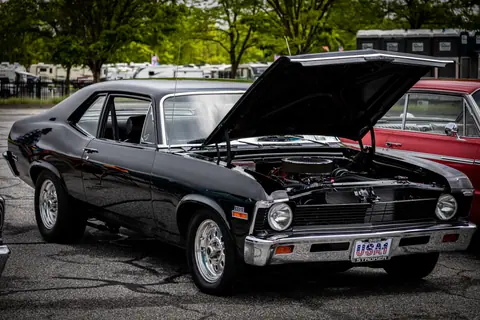 Vintage black car with open hood on display outdoors. Retro style automotive showcase.