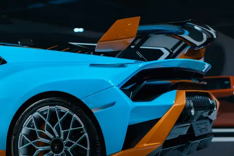 Close-up of a blue and orange sports car showcasing aerodynamic design and stylish alloy wheels.