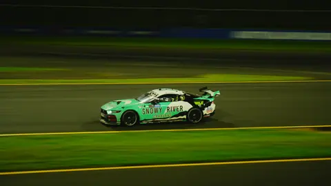 Vibrant race car speeding on track during night race, showcasing dynamic motion.