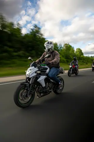 Motorcyclists enjoying a thrilling ride on a scenic road under a cloudy sky.