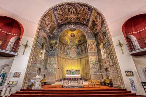 Beautiful interior view of the St John the Baptist Church in England, featuring intricate mosaics and architecture.