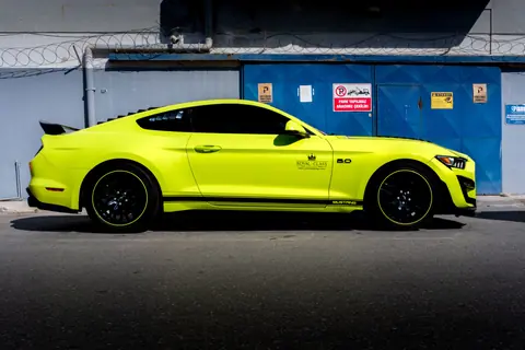 A sleek yellow sports car parked against an industrial backdrop in Türkiye.