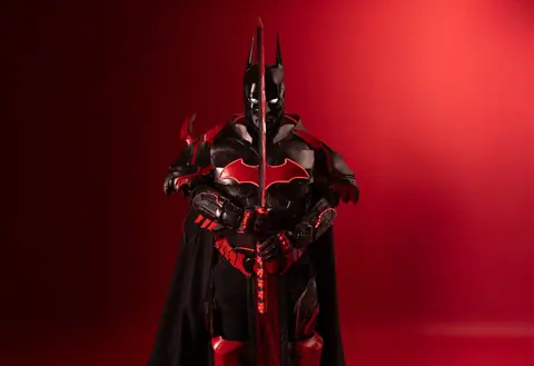 Striking portrait of a person in black and red Batman cosplay armor, showcasing detailed craftsmanship.