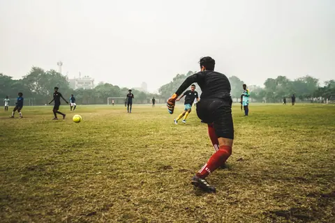 Energetic soccer game with players on a grassy field in India, showcasing teamwork and sportsmanship.