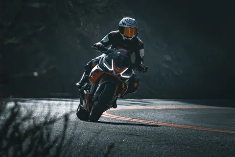 Motorcyclist expertly navigates a sharp curve on a scenic mountain road, showcasing speed and skill.