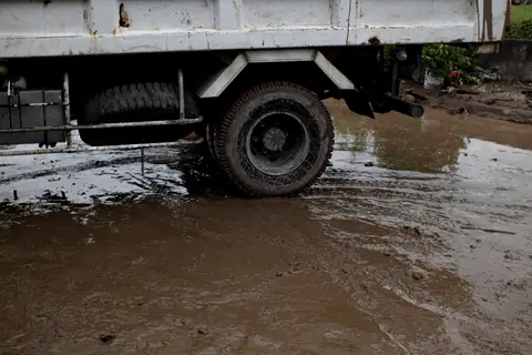 Old transport with rusty surface on roadway with rippled puddle and mud in daylight