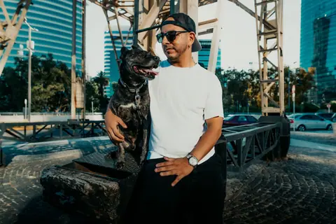 A man and his dog enjoying a sunny day in Buenos Aires' cityscape.