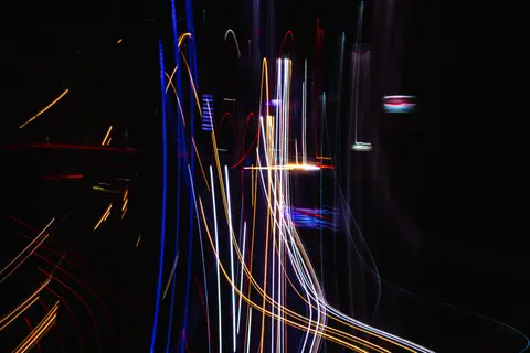 Abstract image of colorful light streaks forming patterns on a dark background.