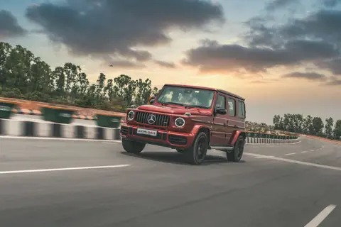 Red Mercedes-Benz SUV speeding on a highway with a cloudy sky backdrop.