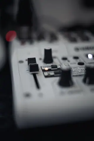 Detailed view of an audio mixer panel with buttons and knobs, in selective focus.