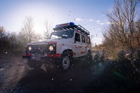 Emergency vehicle driving through mud in winter, creating a dramatic splash.