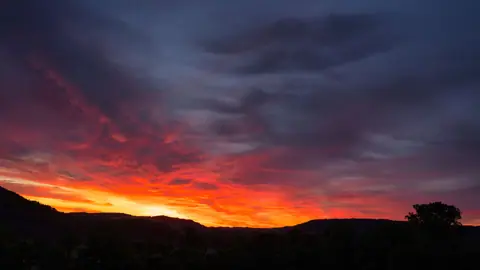 Stunning sunset with vivid colors and silhouetted hills, capturing nature's beauty.