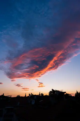Dramatic twilight sky with vibrant clouds over a silhouetted urban skyline.