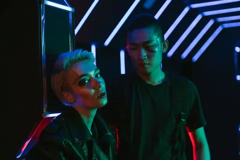 Futuristic cyberpunk scene with two people in neon lighting, embodying modern fashion and style.