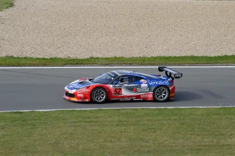 Red and blue sports car racing fast on a gray race track. Motorsport action.