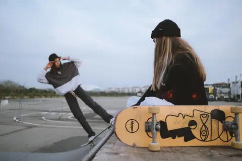 Two female skateboarders showcase skills and style at an urban skatepark, capturing the essence of streetwear and sport.