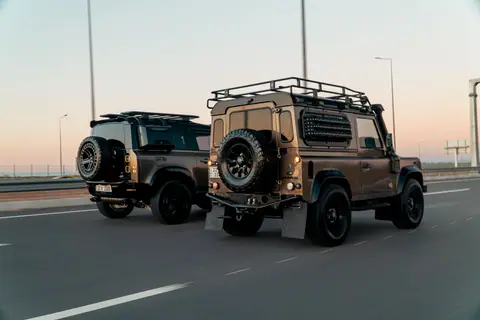 Two Land Rover SUVs driving on a highway in Erbil, Iraq during sunset, showcasing modern automotive design.