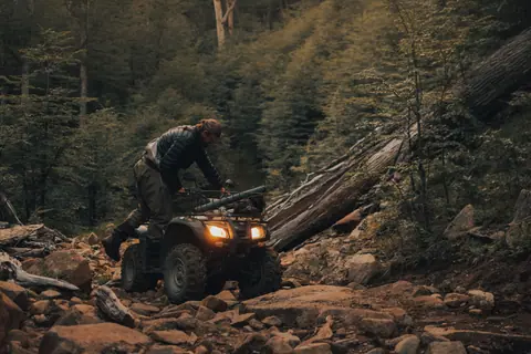 Man riding an ATV on a rugged forest trail, showcasing adventurous outdoor exploration.