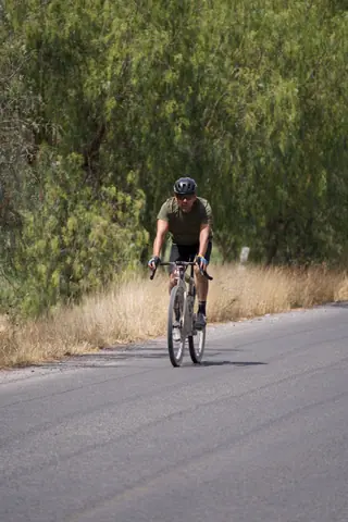 Man cycling on a rural road during summer, wearing sportswear and helmet.