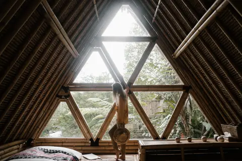 A person stands by a triangular bamboo window, embracing nature indoors.