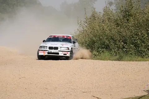 A dynamic rally car speeding through a dusty gravel road in Cesvaine, Latvia.