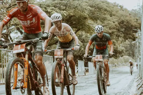 Intense mountain bike race with cyclists battling through rain on a challenging outdoor track.