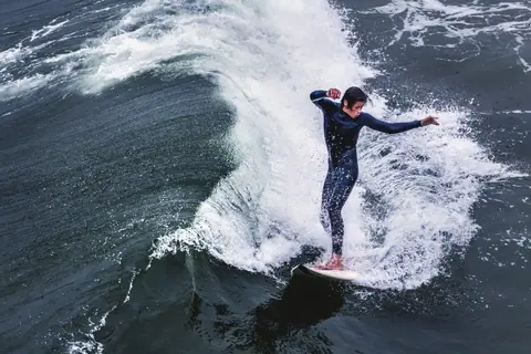Surfer skillfully rides a powerful wave at Pismo Beach, CA, showcasing impressive balance.