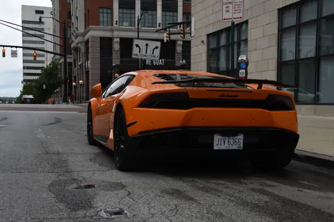 Orange sports car parked on city street, showcasing sleek design and vibrant color.