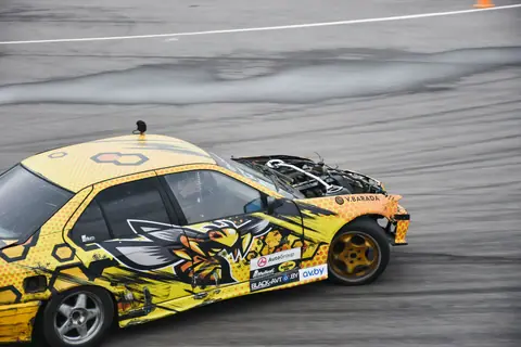 Exciting shot of a colorful drift car speeding on a race track, showcasing vehicle design and motion.