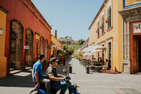 Vibrant street in Tequila, Jalisco with people enjoying a sunny day and colorful architecture.