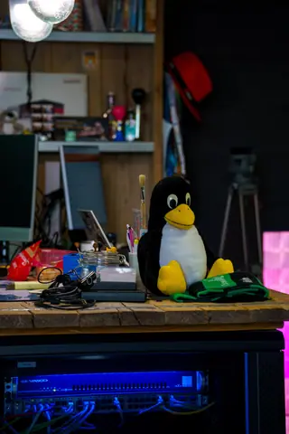 Colorful tech workspace featuring the Tux penguin mascot on a desk.