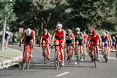 Group of bicyclists in sports suits and helmets riding on bike while taking part in competition in summertime