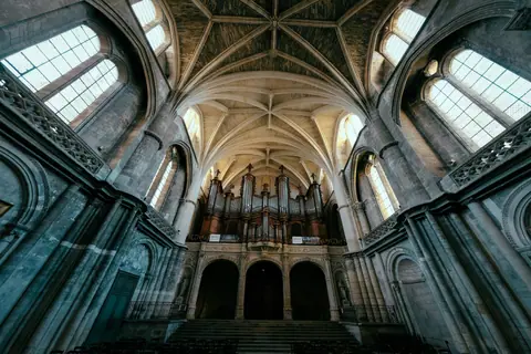Majestic view of a Gothic cathedral interior featuring arched ceilings and a prominent organ.