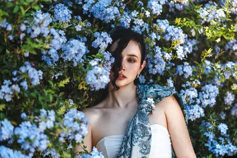 Portrait of a woman in a floral setting with blue flowers in León de los Aldama, Mexico.