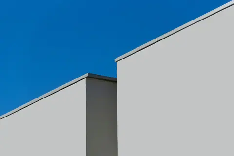 Minimalist modern architecture showcasing geometric lines against a clear blue sky.