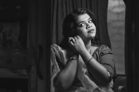 Black and white portrait of a woman adjusting her earrings, exuding elegance and poise.