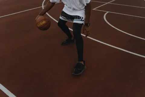 Dynamic shot of a basketball player dribbling on an outdoor court, showcasing athleticism.