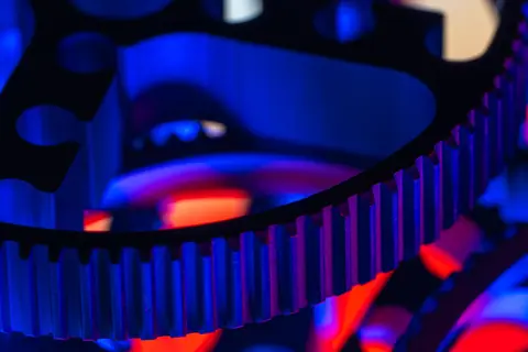 Macro view of metallic gears with striking blue and red lighting showcasing precision engineering.