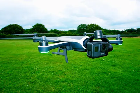 Close-up of a drone equipped with a camera flying over a vibrant green outdoor field.