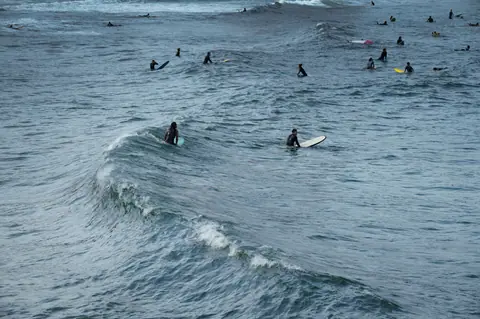 Group of surfers riding waves in the ocean, ideal for adventure and sports enthusiasts.