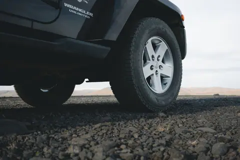 Close-up of an off-road vehicle tire on gravel terrain, ideal for travel and exploration themes.