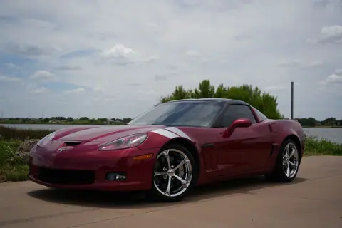 Red Corvette sports car parked on a scenic road in Wichita Falls, Texas, under a cloudy sky.