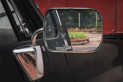 A close-up view of a car's side mirror reflecting a scenic outdoor area.