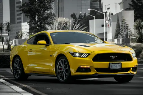 Dynamic shot of a yellow sports car cruising on a city street, showcasing urban elegance.