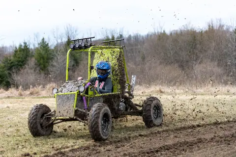 Exciting off-road go-kart racing through muddy terrain with splashes of dirt.
