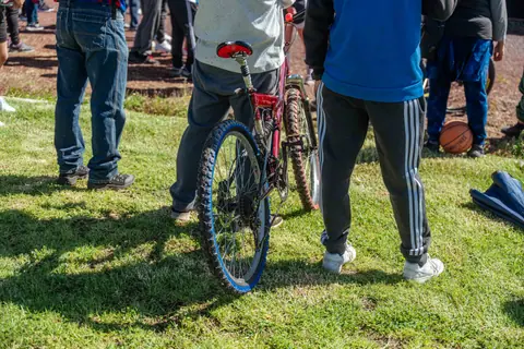 People at an outdoor event with a bicycle and basketball on grass.