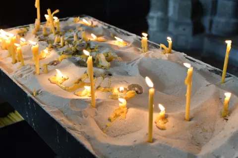 Candles burning in sand inside a Vienna church, creating a serene atmosphere.