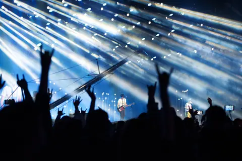 Energetic live music performance with crowd cheering under dramatic lighting.