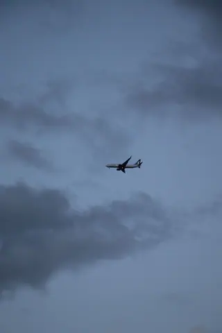 A passenger airplane flying in a cloudy sky during dusk, capturing a serene travel moment.